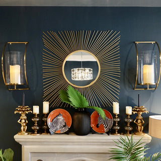 Gold Finish Starburst Mirror on Dark Wall Above Fireplace